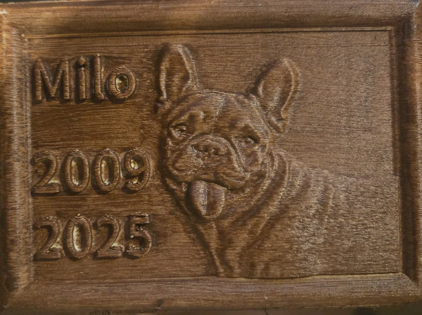 A wood-finish Tazbear relief of a dog named Milo, 2009 to 2025